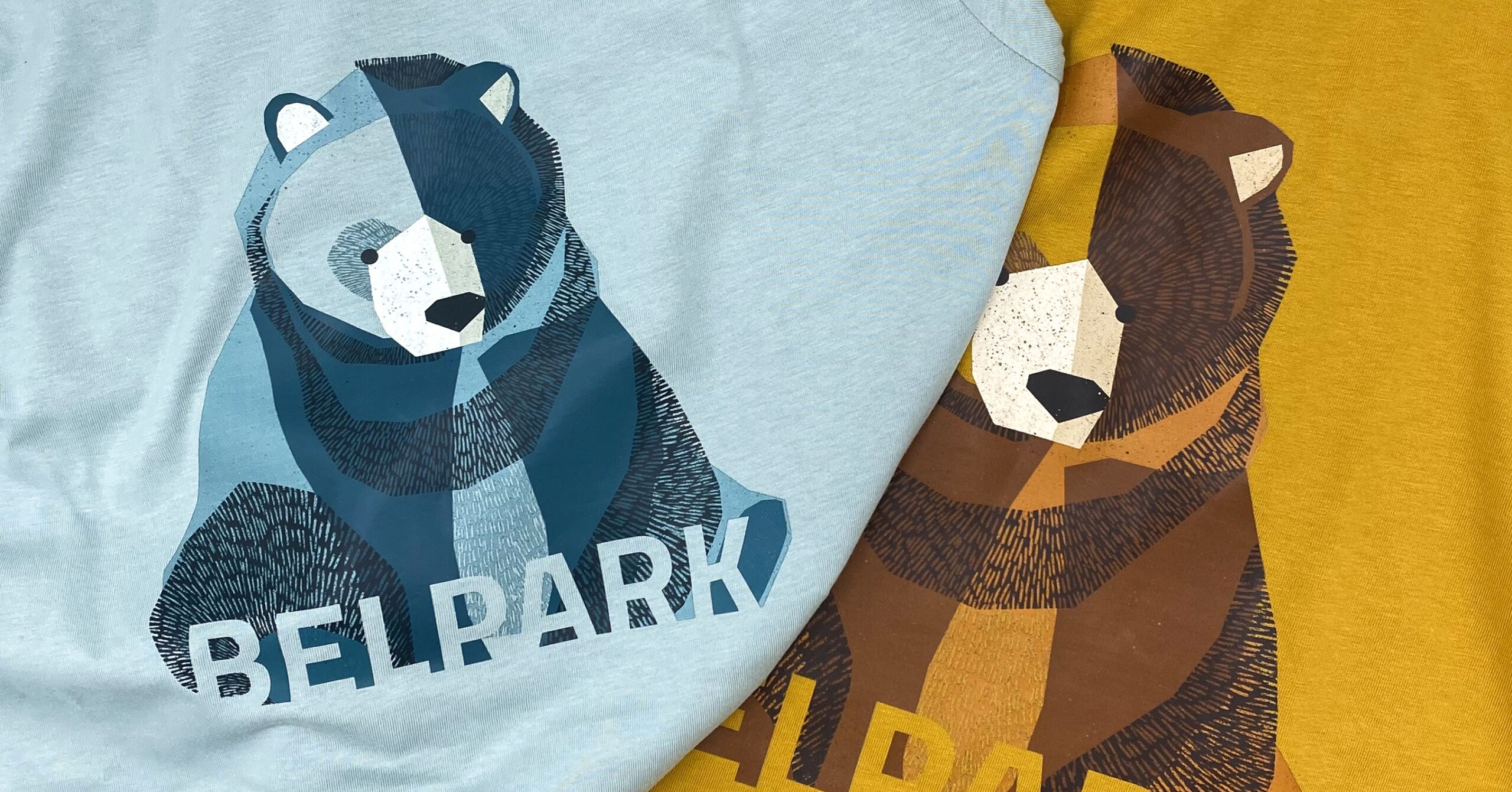 Due t-shirt colorate con illustrazione stilizzata di un orso, realizzate per BelPark.
